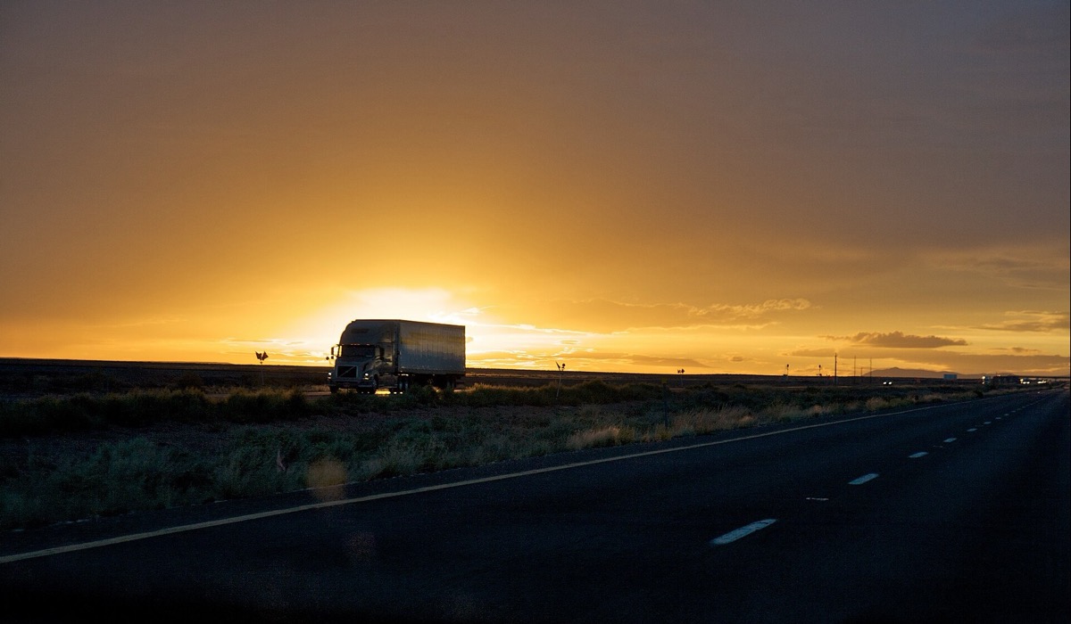 Lone semi truck silhouetted against an interstate sunset