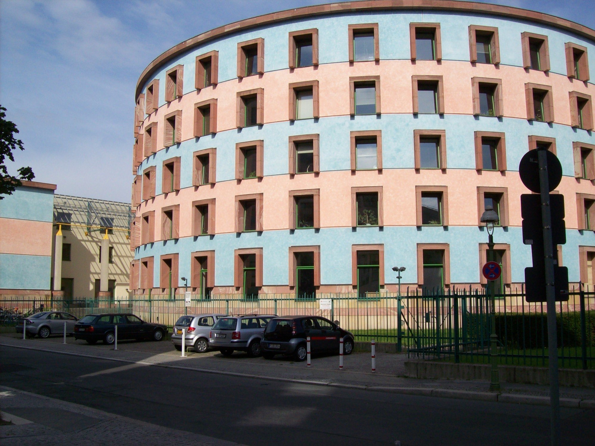 The curved pink and blue facade of the WZB building in Berlin, five storeys of square windows on a drum